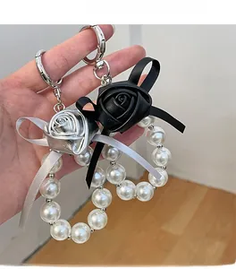 Detailed view of rose PU leather keychain with white pearls and satin ribbon charms