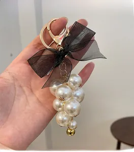 Detail of the elegant black ribbon bow and white grape-shaped pearls on a gold keychain