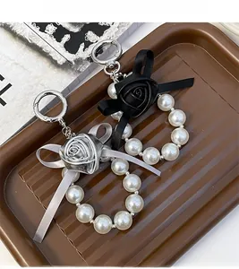 Detail view of pearl bead keychain with black and silver roses and elegant ribbon bow