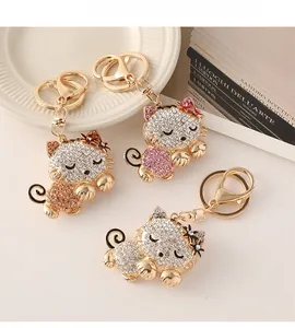 Detailed close-up of rhinestone-encrusted cat keychains in pink and gold on a tray