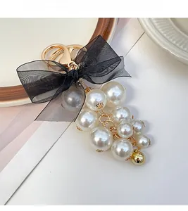 Close-up of translucent black organza bow and cream pearl grape cluster keychain