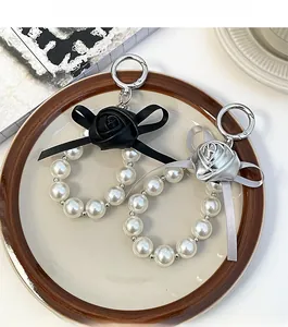 Detail of rose and pearl keychains in black and silver finishes on a ceramic plate
