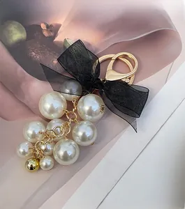 Detail of elegant black organza bow and clustered faux pearls on a golden keychain