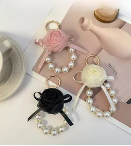 Detail of elegant pearl ring and mesh rose flower keychain charms in three colors