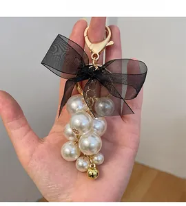 Detail of elegant pearl cluster and black mesh bow accessory with gold bell pendant
