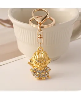 Close-up of golden Monkey King keychain with white rhinestones on a white striped cup