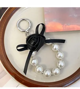 Detail of elegant pearl keychain featuring black rose, satin bow, and silver spring clasp