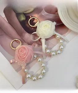 Detailed close-up of handmade chiffon rose and pearl bead keychains in pink and cream