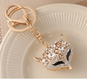 Dettaglio portachiavi a testa di volpe con strass brillanti e chiusura dorata su un piatto
