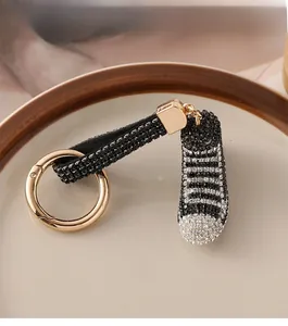 Dettaglio di un portachiavi a forma di mini sneaker con strass neri e bianchi
