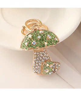 Close-up of a gold alloy mushroom keychain featuring green and white rhinestones