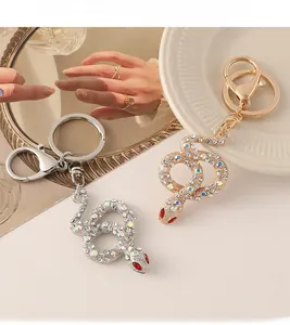 Detail of gold and silver snake keychains with sparkling crystals and red gemstone eyes