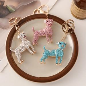 Dog pendant keychains with sparkly crystals in white, pink, and blue on a tray