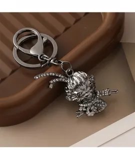 Détail du porte-clés Roi Singe en métal noir avec strass brillants sur plateau