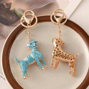Dog zodiac keychains with blue rhinestones and gold floral patterns on a ceramic plate
