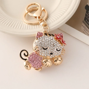 Golden cat keychain with white and pink rhinestones on elegant decorative background