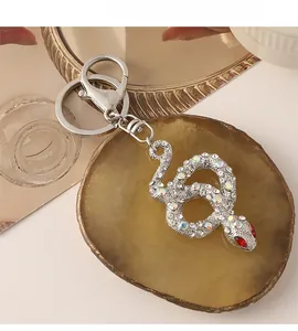 Close-up of snake keychain with sparkling rhinestones on amber agate stone background
