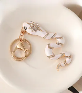 Detailed close-up of white enamel snake keychain with sparkling crystal embellishments