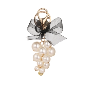 Grape pearl cluster keychain with black organza bow and golden clasp on white background