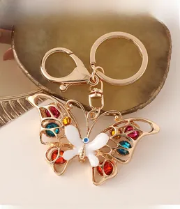 Detail of colorful rhinestone butterfly keychain with gold metal frame on agate background