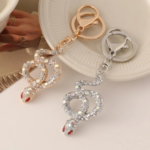 Elegant gold and silver snake keychains with sparkling crystals on white porcelain