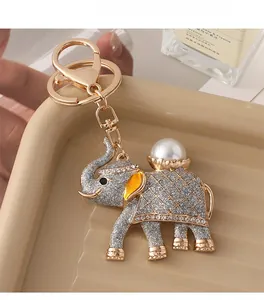 Detail of elephant keychain with white pearl and sparkling glitter finish on golden tray