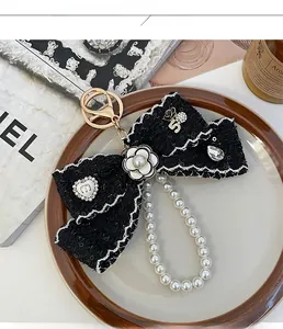 Detail view of tweed camellia bow keychain with pearl charms and gold lobster clasp