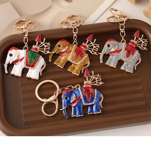 Détails de quatre porte-clés éléphant en émail coloré avec cristaux sur plateau en bois
