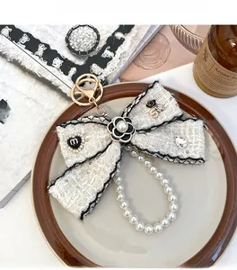 Detail of tweed bow keychain with camellia flower, pearls and gold lobster clasp