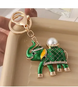 Macro view of vintage gold elephant keychain with green enamel, pearl, and rhinestones