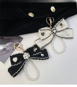 Detail of tweed camellia bow charms with pearls and gold metal accents for bags