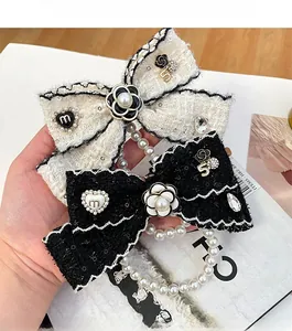 Detail of tweed bow keychains with camellia flower, pearl tassels and number 5 charms