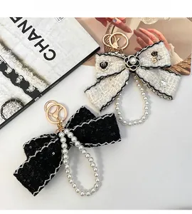 Detailed view of tweed camellia bow keychain with pearl chain and rhinestone number five