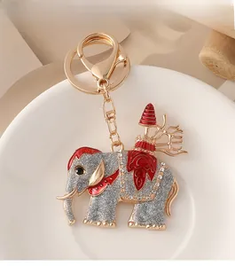 Vue détaillée d'un porte-clés éléphant doré avec paillettes argentées et émail rouge