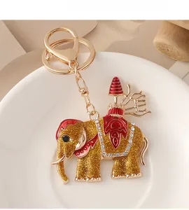 Détail du porte-clés éléphant doré avec émail rouge et strass blancs sur assiette blanche