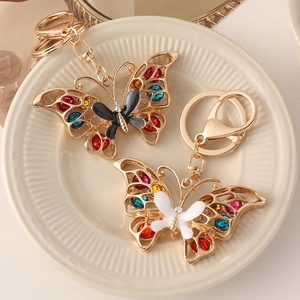 Golden butterfly keychain with colorful rhinestones on an elegant ceramic plate