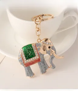 Close-up of golden elephant keychain with sparkling grey finish and green enamel saddle