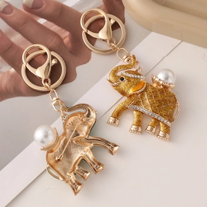 Golden elephant keychain with rhinestones and pearls on a stylish magazine background