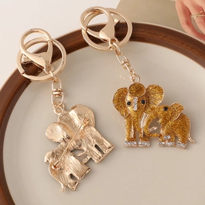 Golden elephant keychain with glitter and rhinestones, set of two on a ceramic plate