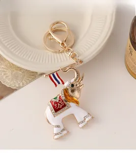 Close-up of golden elephant keychain with white enamel, colorful saddle and rhinestones