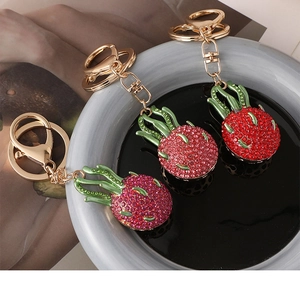 Close-up of sparkling rhinestone dragon fruit keychains on a dark ceramic tray