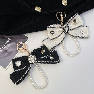 Elegant camellia bow keychain with pearl chain and tweed fabric in black and white