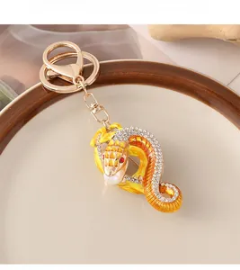 Détail d'un porte-clés serpent doré orné de strass brillants et d'une perle blanche