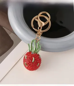 Detailed view of red rhinestone dragon fruit keychain with gold hardware on a display tray
