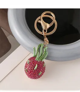Detail of sparkling rhinestone dragon fruit keychain with gold clasp on ceramic plate