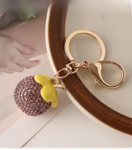 Close-up of purple rhinestone mangosteen keychain with golden lobster clasp on a white plate