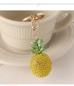 Detailed close-up of a sparkling gold pineapple keychain with yellow rhinestones on a cup