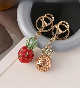 Detailed close-up of dragon fruit keychains with red rhinestones and golden lobster clasp