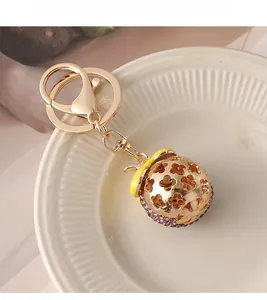 Close-up of golden mangosteen keychain featuring pink rhinestones and floral hollow design