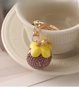 Detail of mangosteen keychain with purple rhinestones hanging on a ceramic coffee cup